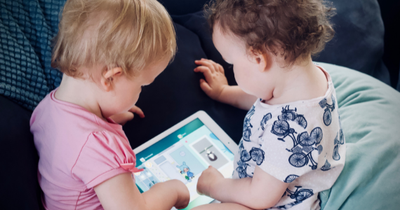Two young toddlers playing on an iPad