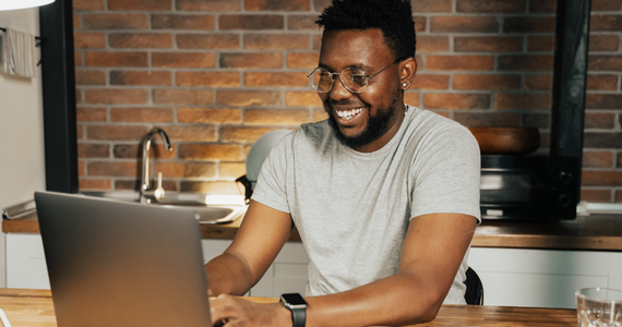 smiling man using laptop in kitchen